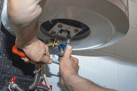 Close-up of a person repairing the bottom of a water heater.