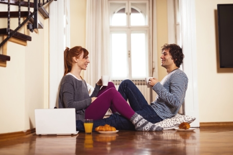 A couple sits on the floor, enjoying coffee and croissants together.