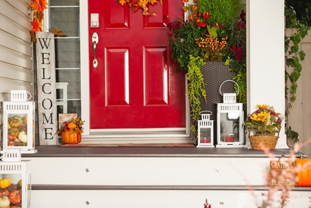 A charming red door adorned with seasonal decorations creates a warm, inviting autumn welcome.